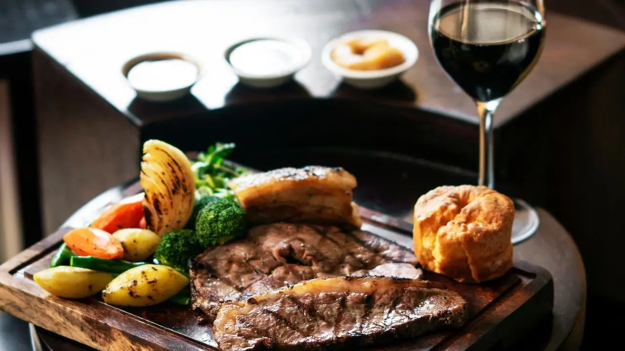 Full platter of roasted meat, vegetable sides, yorkshire pudding and red wine